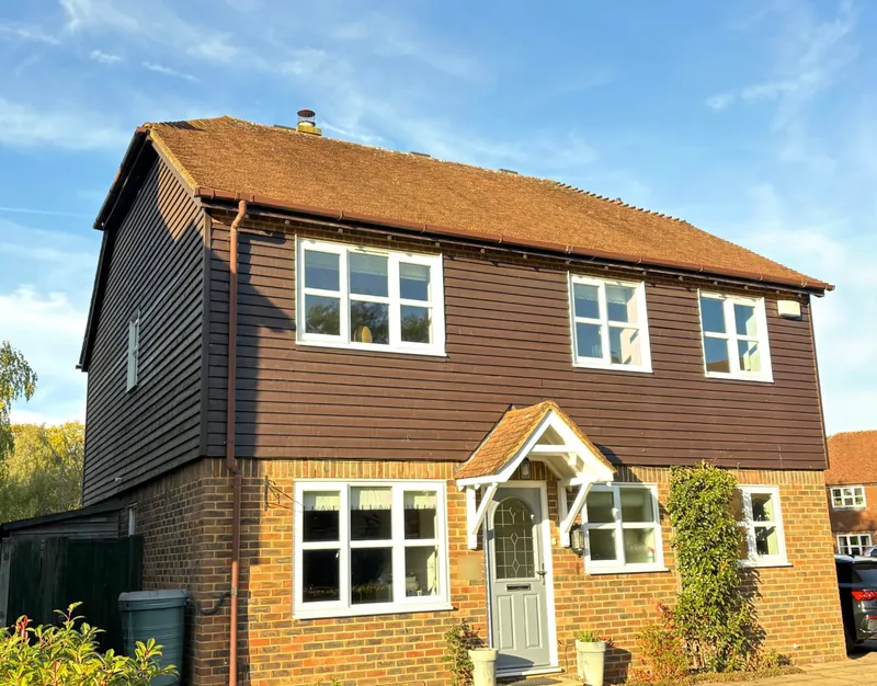 Front of the house in the sun with clean roof tiles and gutters